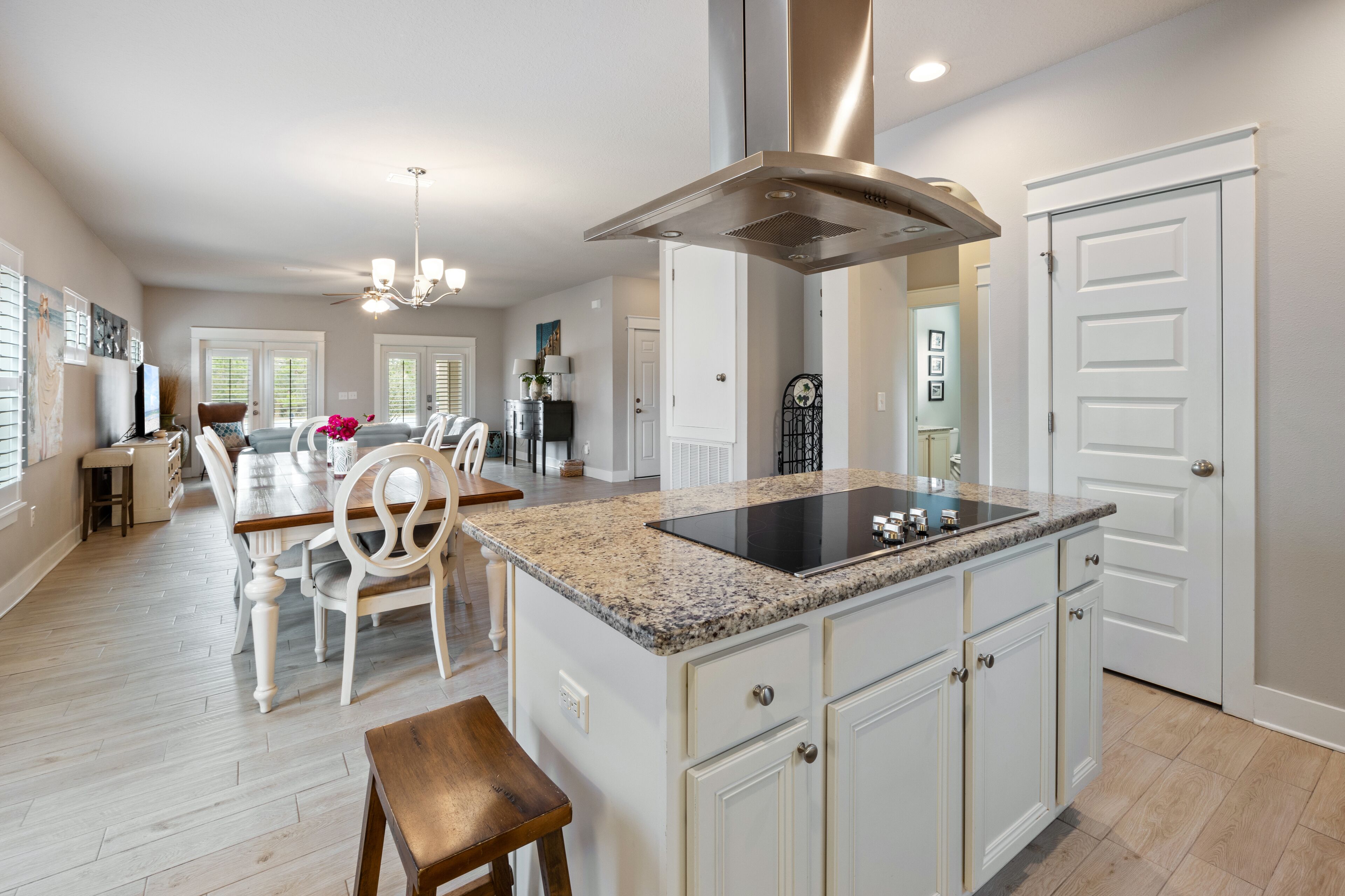 A spacious kitchen with a central island, white cabinetry, and a modern stainless steel range hood.