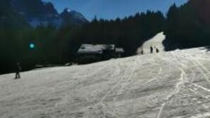 Paesaggio montano innevato con cielo sereno e sole splendente.