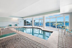 Swim laps in the pool surrounded by a clear view of the sea through large windows.