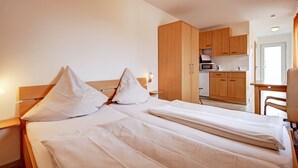 Una habitación de hotel con cama, escritorio y kitchenette.