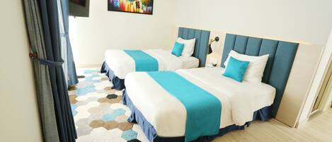 A hotel room with two beds, a colorful hexagonal rug, and a painting on the wall.