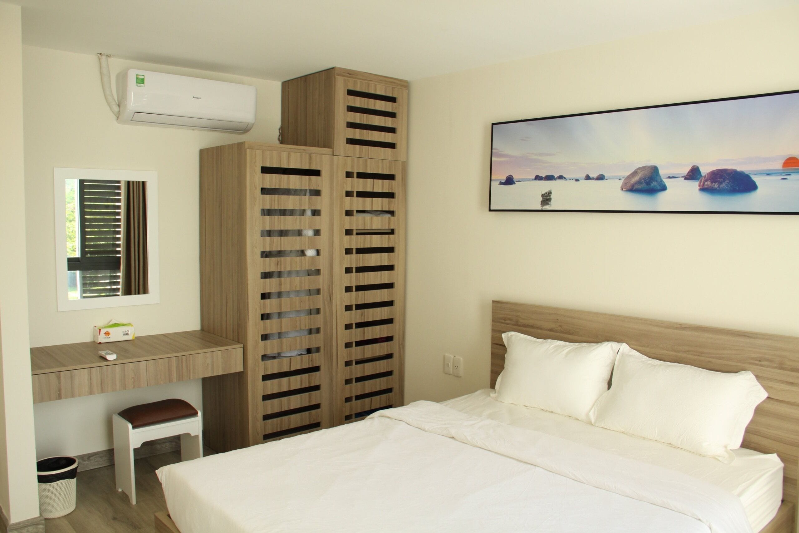 Un dormitorio con cama, escritorio y un amplio ventanal.