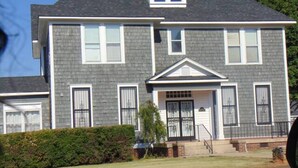A two-story house with a front porch, a garage, and a well-maintained lawn. - Peace Apartment, upstairs with king size bed. (Anniston)