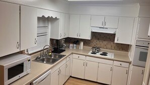 A modern kitchen with white cabinets, a stainless steel sink, a microwave, a stove, and a dishwasher. - Peace Apartment, upstairs with king size bed. (Anniston)