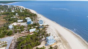 Vue aérienne d’une zone côtière avec une plage, des maisons et une vaste étendue d’eau.
