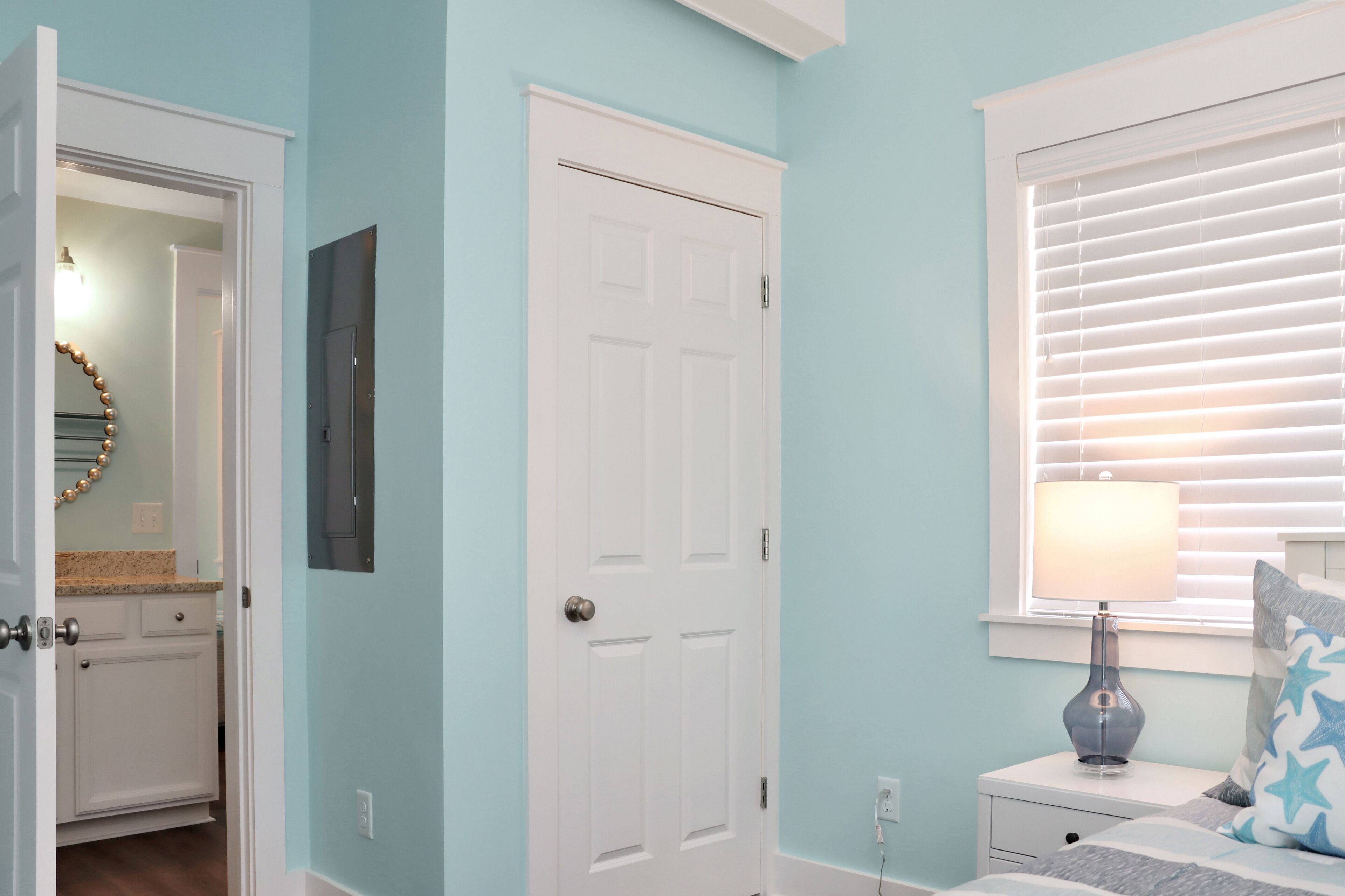 A bedroom with a bed, nightstand, lamp, and window with blinds.