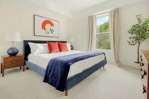 A bedroom with a bed, nightstands, a window with curtains, a plant, and a wall art piece. - Heart of Olde Town | Urban Retreat | 95 Walk Score (Arvada)