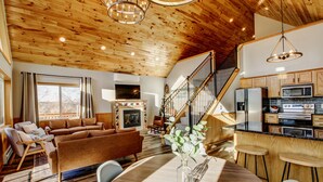A spacious living room with a fireplace, a dining area with a table, and a kitchen with modern appliances.