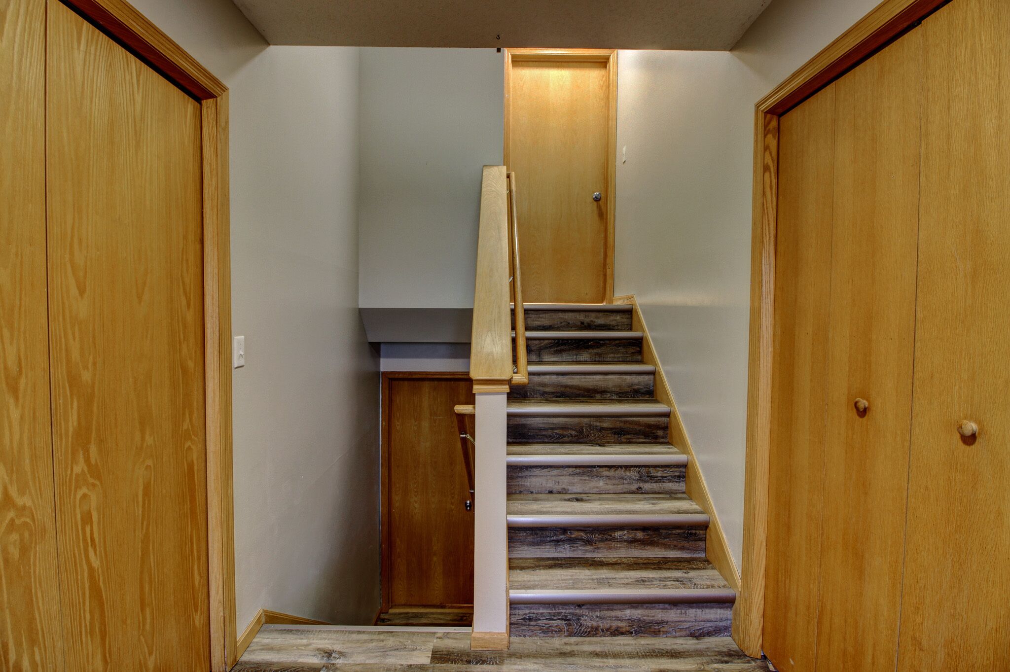 A wooden staircase with a handrail leading to a door at the top.