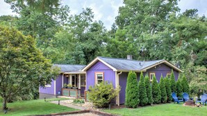 A single-story house with a purple exterior, a front porch, and a well-maintained lawn.