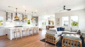 A spacious living area with a large sofa, wooden chairs, and a dining table. - Altair House at Lunara Bay (Key West)