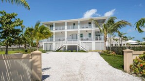 A two-story building with a central staircase, surrounded by palm trees and a gravel driveway. - Altair House at Lunara Bay (Key West)