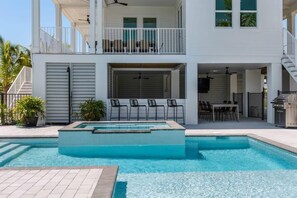 Ein zweistöckiges Gebäude mit Swimmingpool, Außenbereich mit Sitzgelegenheiten und einer überdachten Terrasse.
