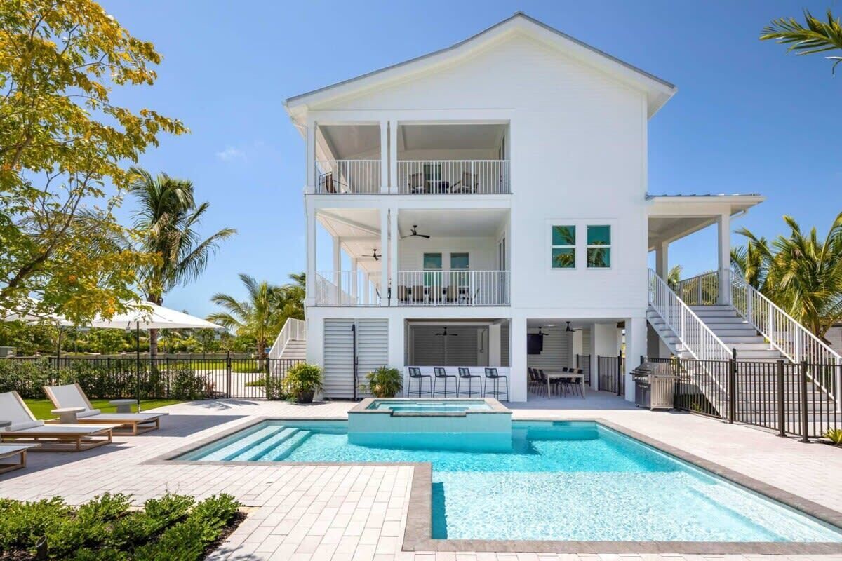 A two-story building with a swimming pool, outdoor seating, and a staircase.