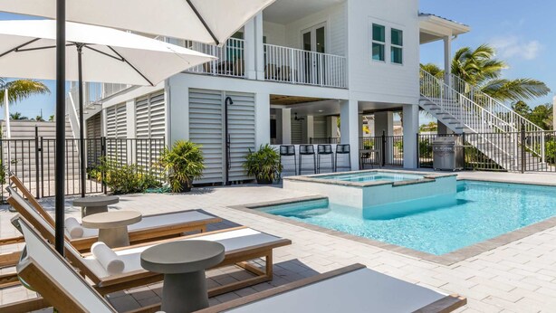 A two-story building with a swimming pool, outdoor seating, and a covered patio area. - Altair House at Lunara Bay (Key West)