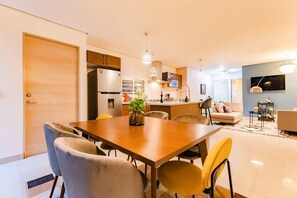 Un salon moderne comprenant une table à manger, des chaises, un canapé et un téléviseur.