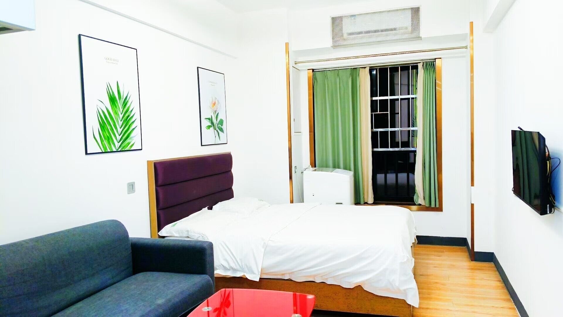 Una habitación de hotel compacta con cama, sofá, televisión y ventana con cortinas.