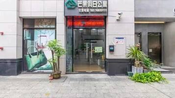 A building with a glass entrance, a green logo, and a contact number.