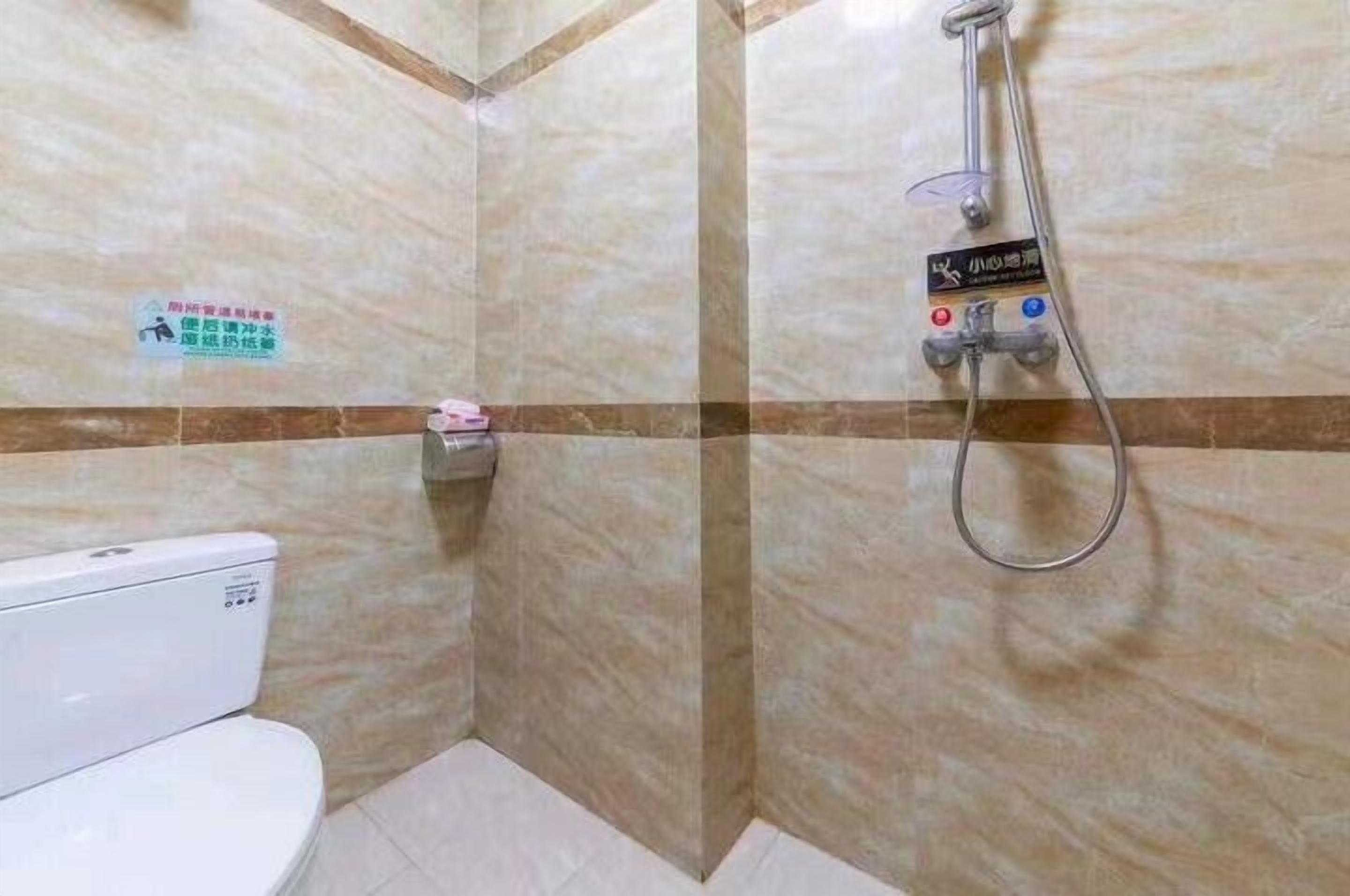 Et badeværelse med toilet, bruser og et skilt på væggen.