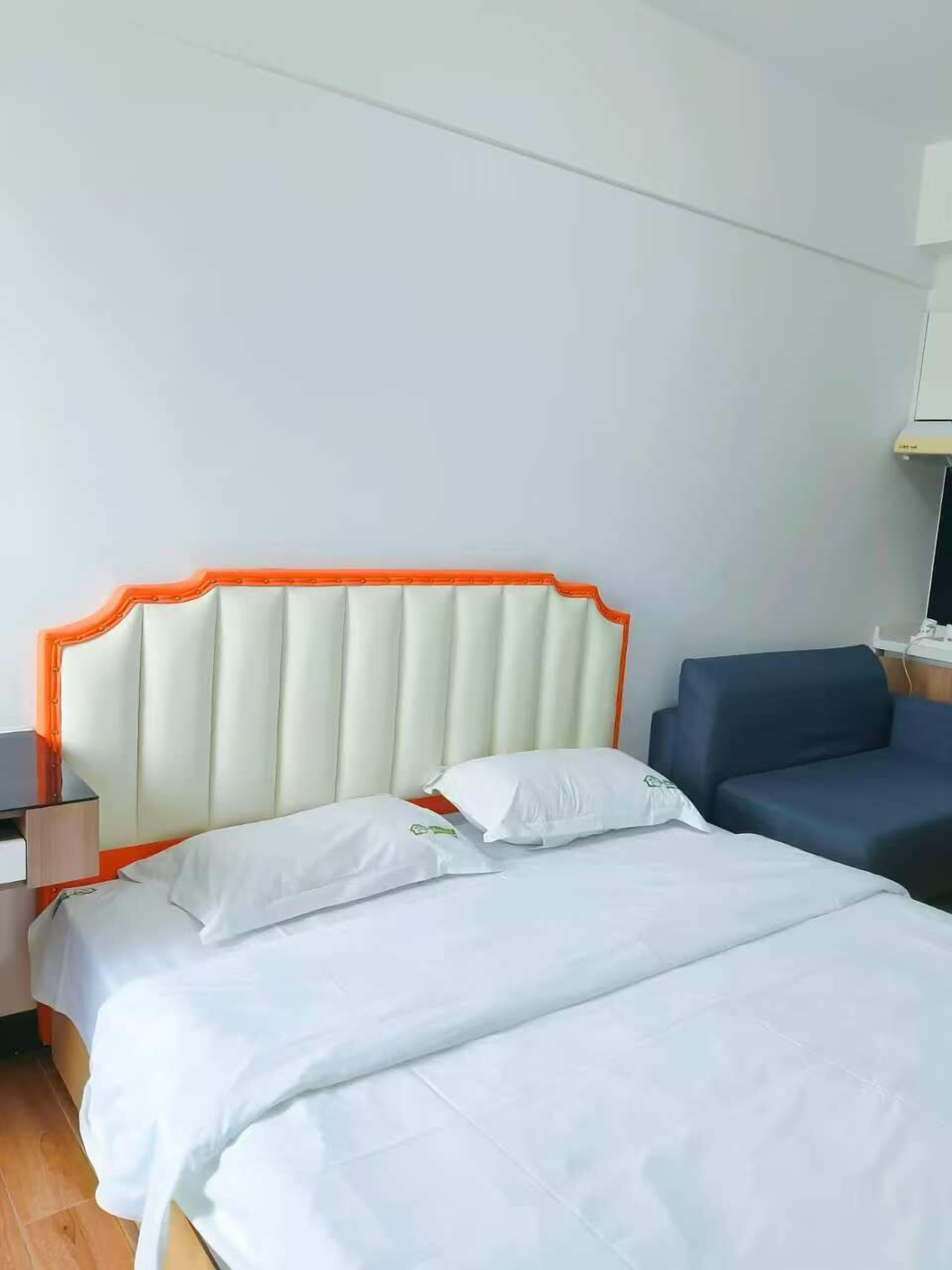 Une chambre d’hôtel avec deux lits, une table de chevet, une lampe et un canapé bleu.