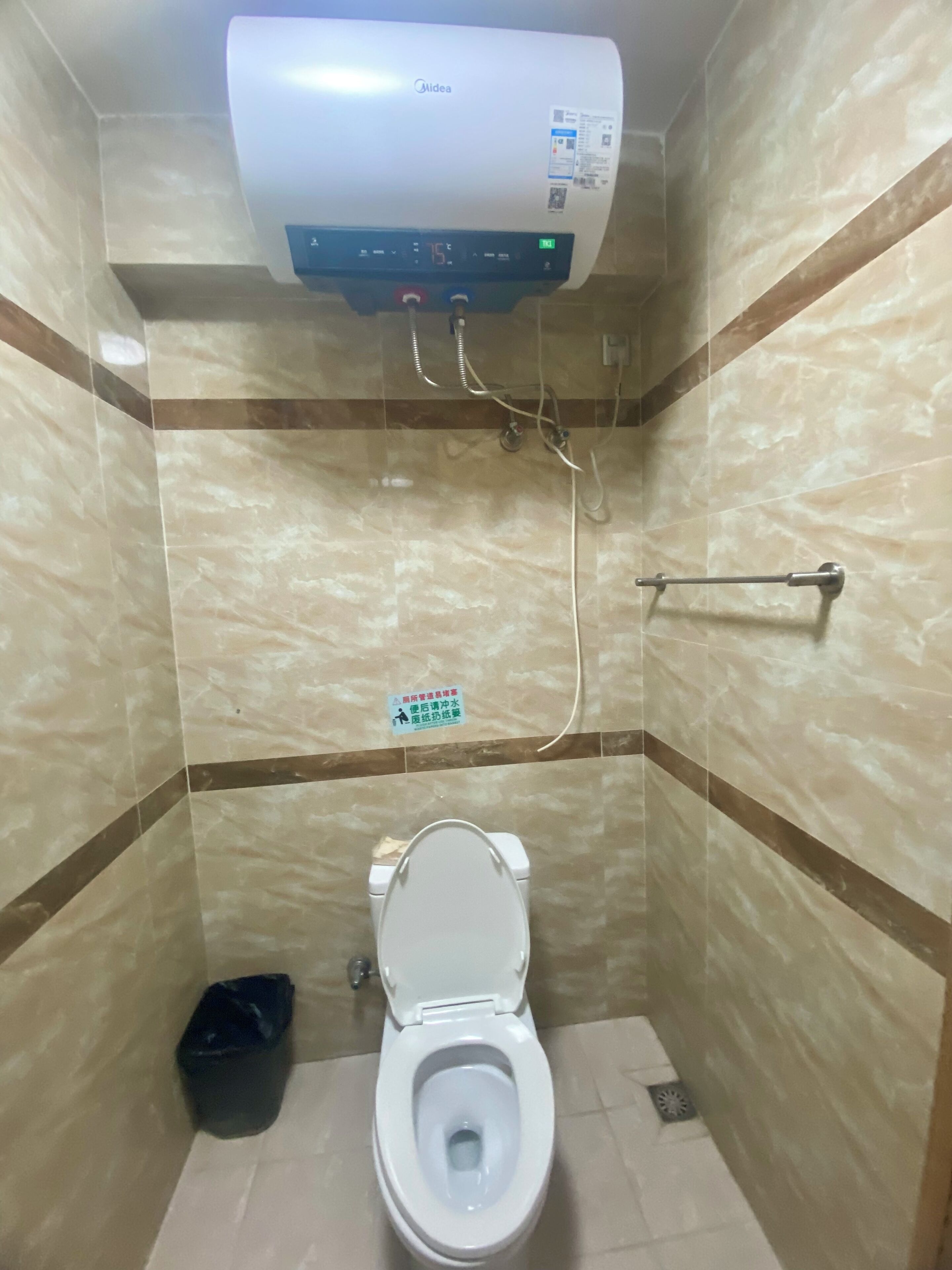 Ein kleines Badezimmer mit Toilette, Handtrockner und Wand-Klimaanlage.