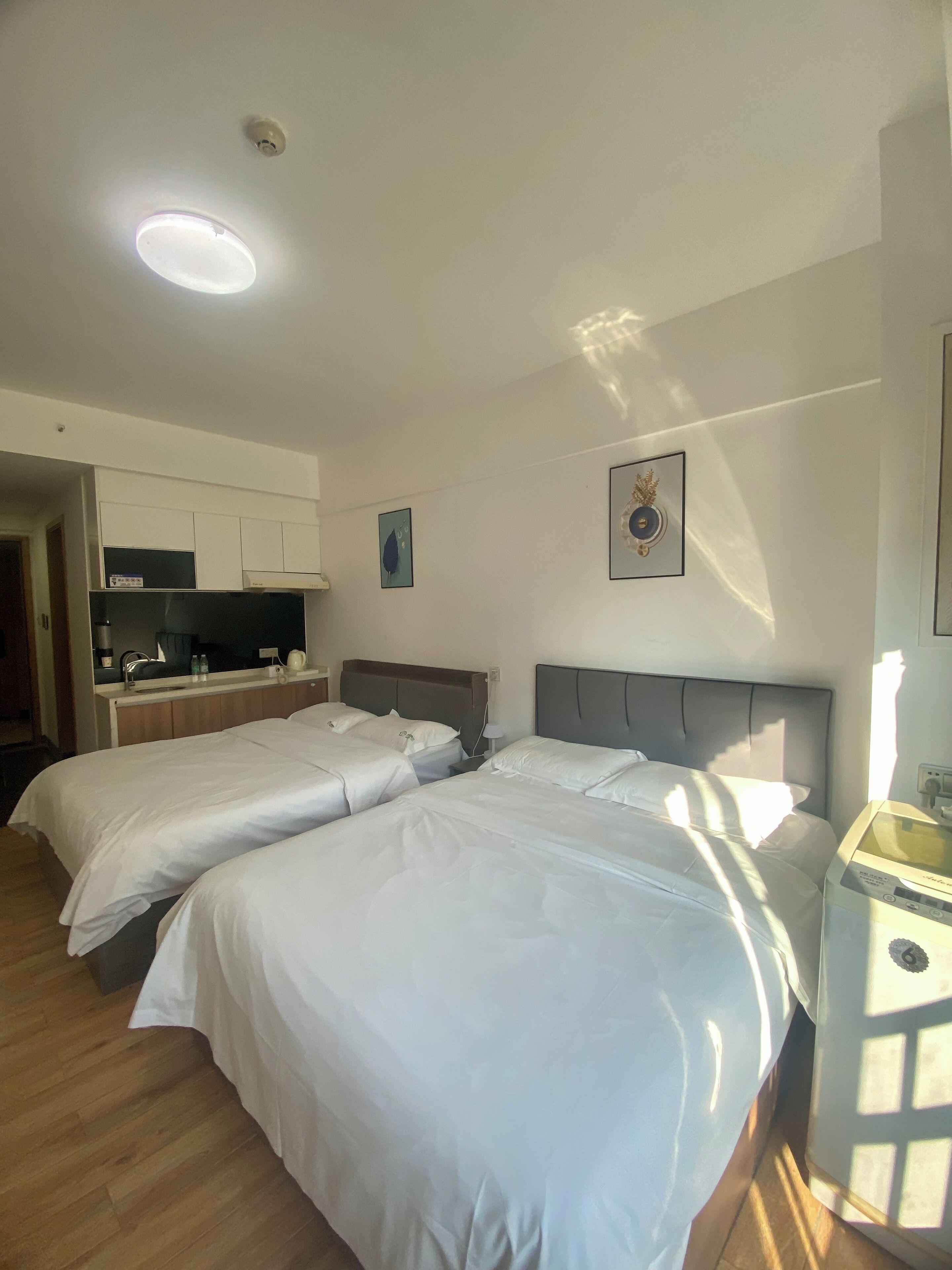 Ein Hotelzimmer mit zwei Betten, einer Küchenzeile, einem Badezimmer und einer kleinen Sitzecke.