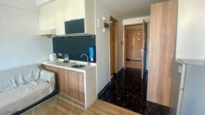 A modern kitchen with a built-in stove, a sink, and a countertop. There is a wooden floor and a glass table in the foreground. - ManGo Holiday Internation Apartment (Dongguan)