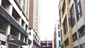 A pedestrian street with buildings on either side, a playground with swings and a slide, and a small blue vehicle. - ManGo Holiday Internation Apartment (Dongguan)