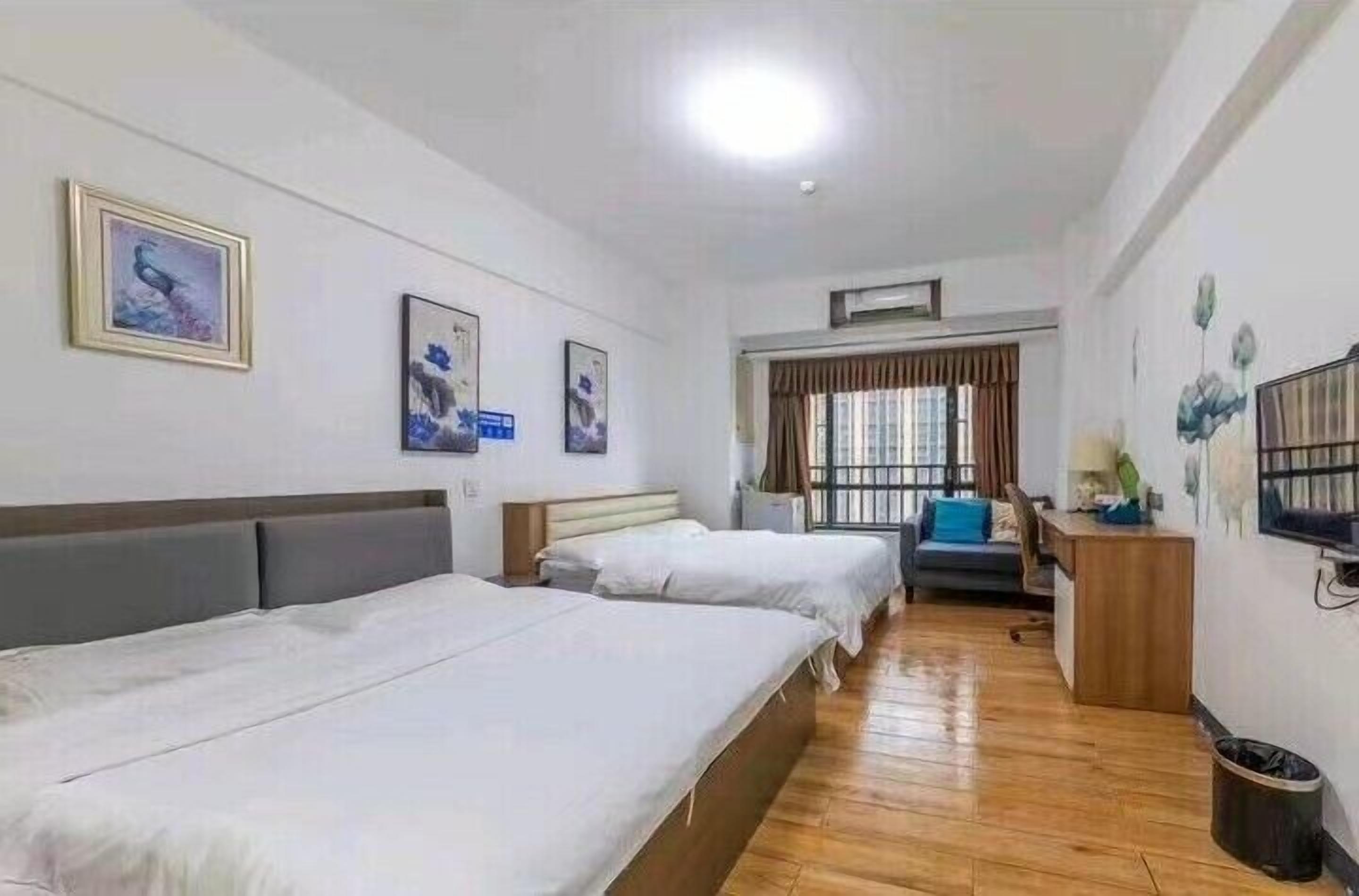 A hotel room with two beds, a desk, a chair, and a window with curtains.