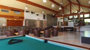 Un área de piscina con diversas opciones de asientos, una zona de bar y un muro de piedra.