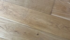 Primer plano de un suelo de madera con tablones y nudos visibles.