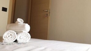 A hotel room with a bed, a wooden door, an air conditioning unit, and a wooden hanger rack. - Dabbanna home (Chiaramonte Gulfi)