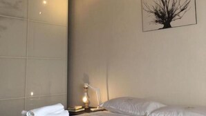 A bedroom with a bed, a wall-mounted light, a framed artwork, and a bedside table with a lamp. - Dabbanna home (Chiaramonte Gulfi)