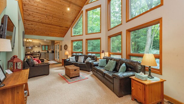 A spacious living room with a high ceiling and large windows, a fireplace, and a cozy seating area. - Secluded Lake Escape w/ Dock, Fire Pit & Views (Oakland)