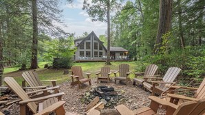 A cabin with a deck and a fire pit surrounded by Adirondack chairs. - Secluded Lake Escape w/ Dock, Fire Pit & Views (Oakland)