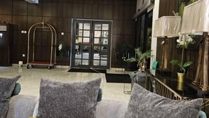 A modern lobby with grey sofas, yellow cushions, a wooden wall, and a large abstract painting. - Melbrooke Park Hotel (Lekki)