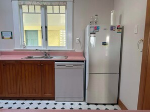 A compact kitchen with a sink, wooden cabinets, a dishwasher, and a refrigerator.