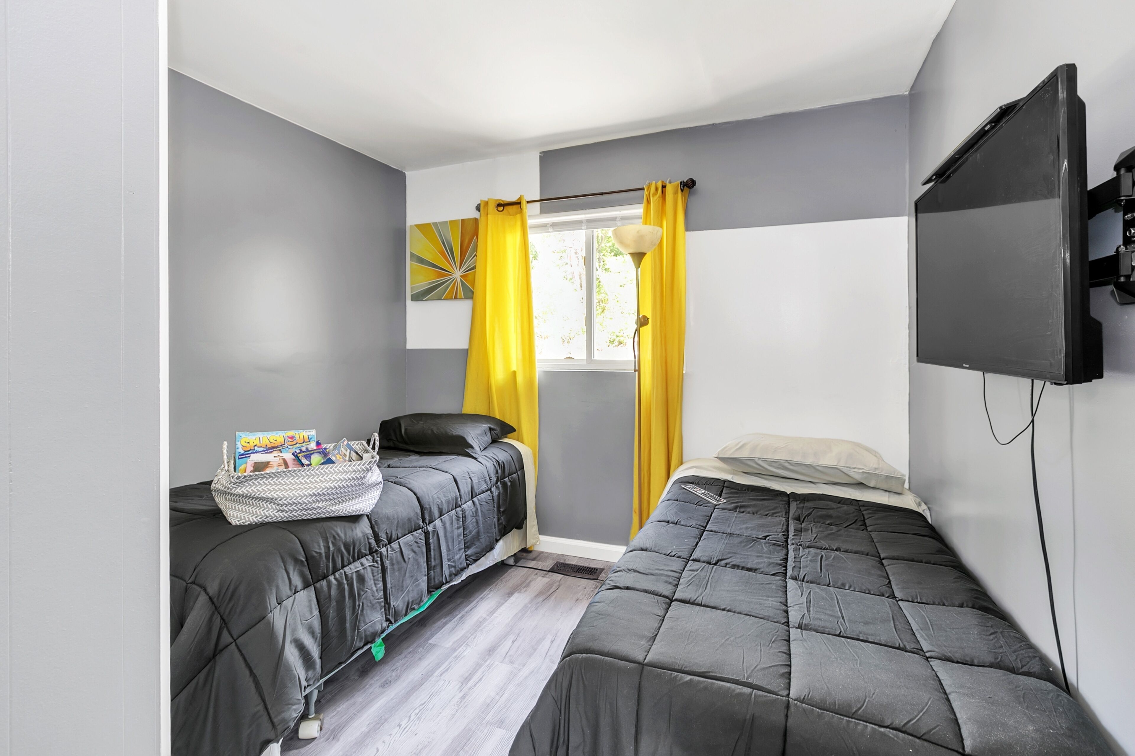 Une chambre avec deux lits, une télévision et une fenêtre avec des rideaux.