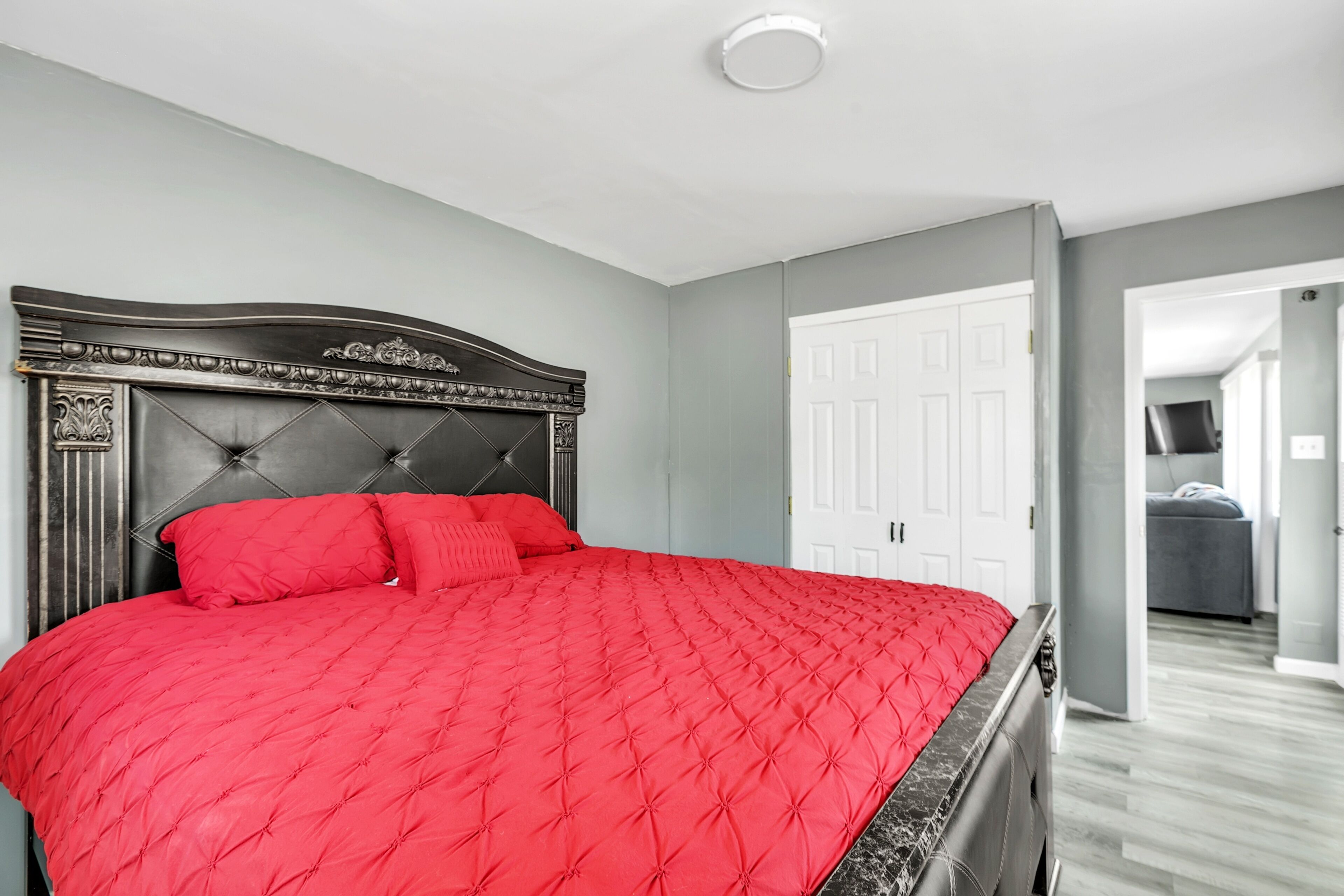 A bedroom with a large bed, a dark headboard, and a white door.