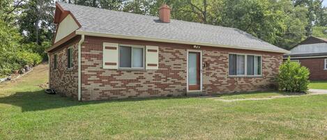 A single-story brick house with a gabled roof and a chimney.