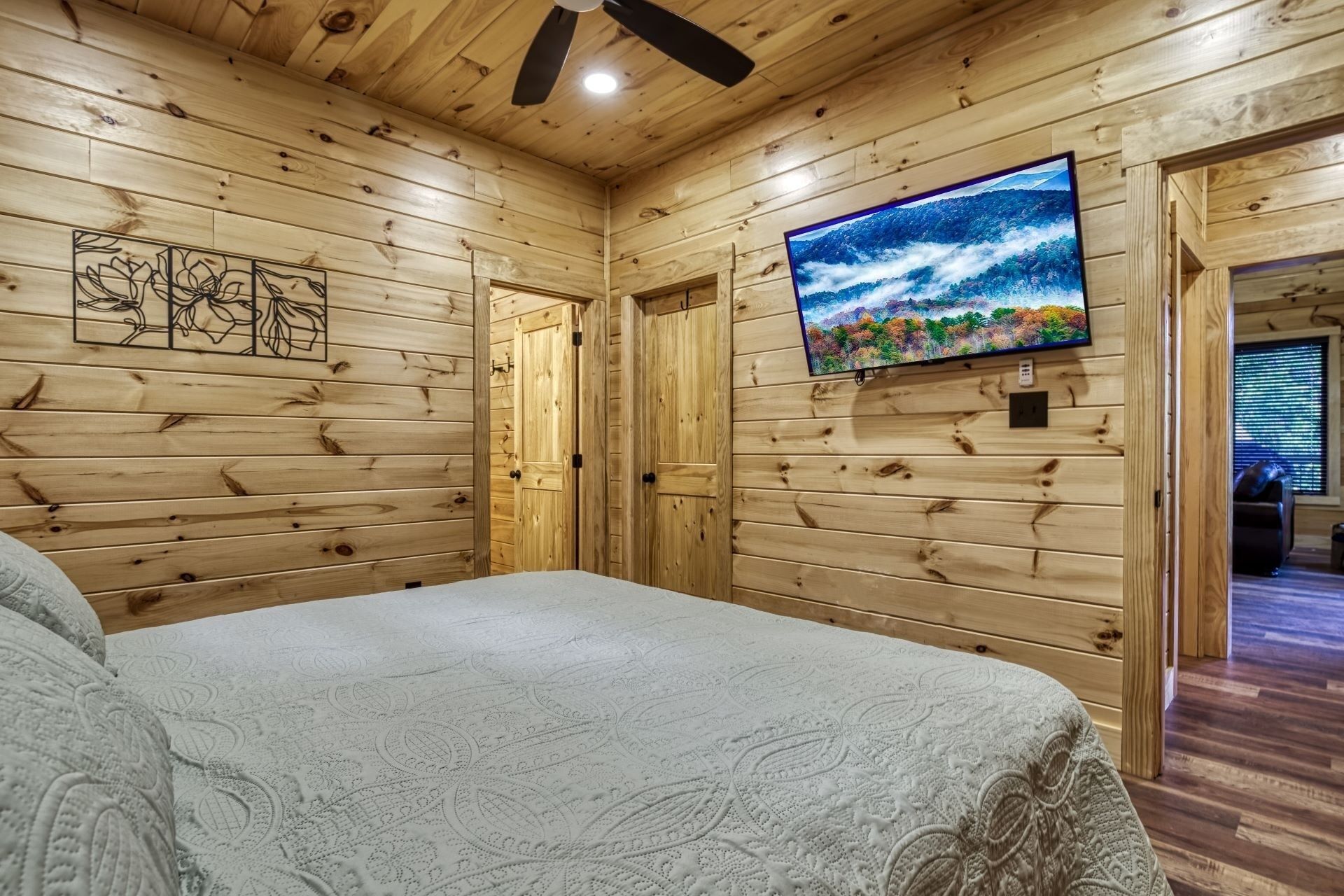 Una habitación con paneles de madera, una cama, un televisor y un ventilador de techo.