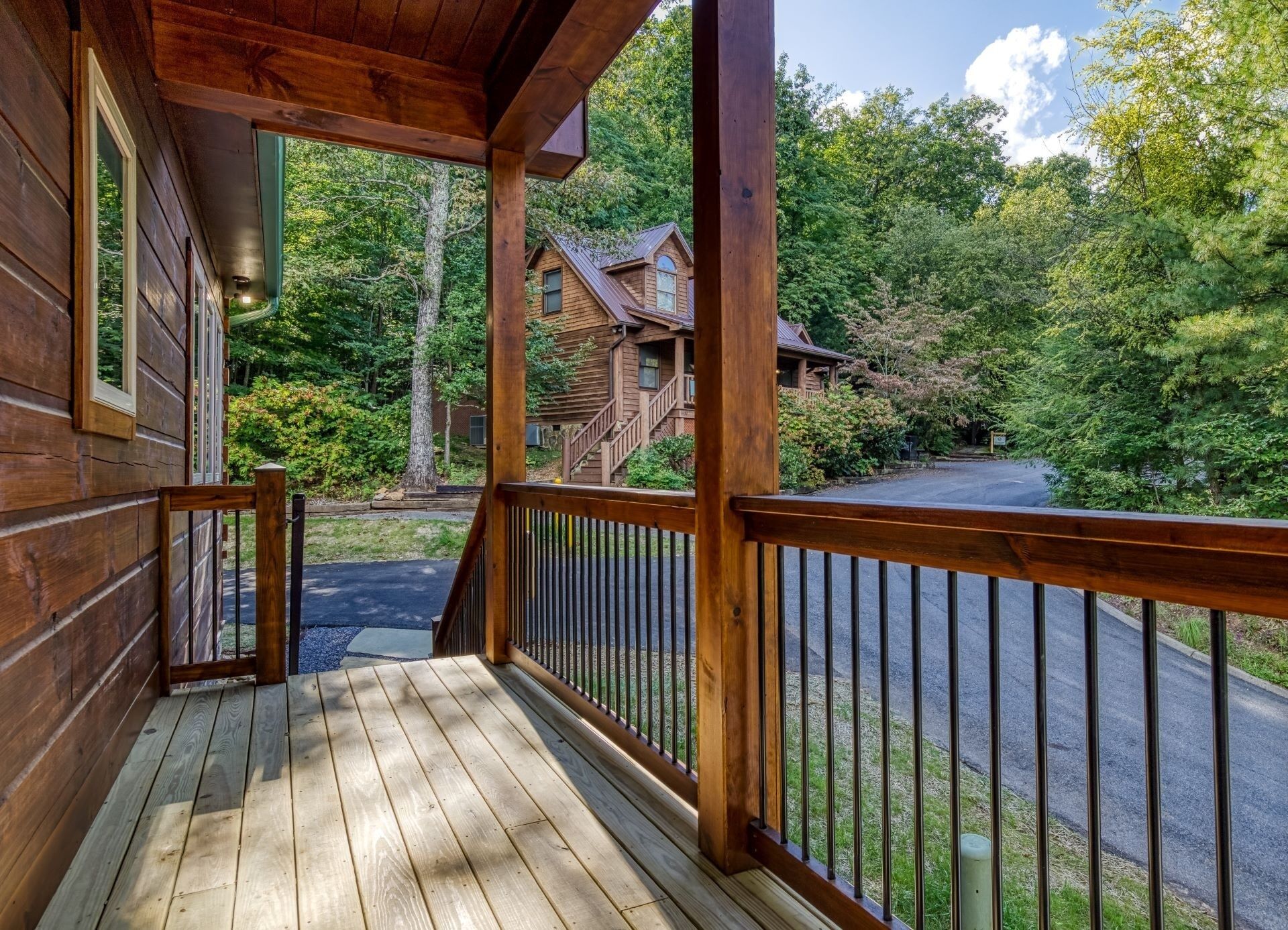 A wooden cabin with a porch, surrounded by dense forest and a clear sky.