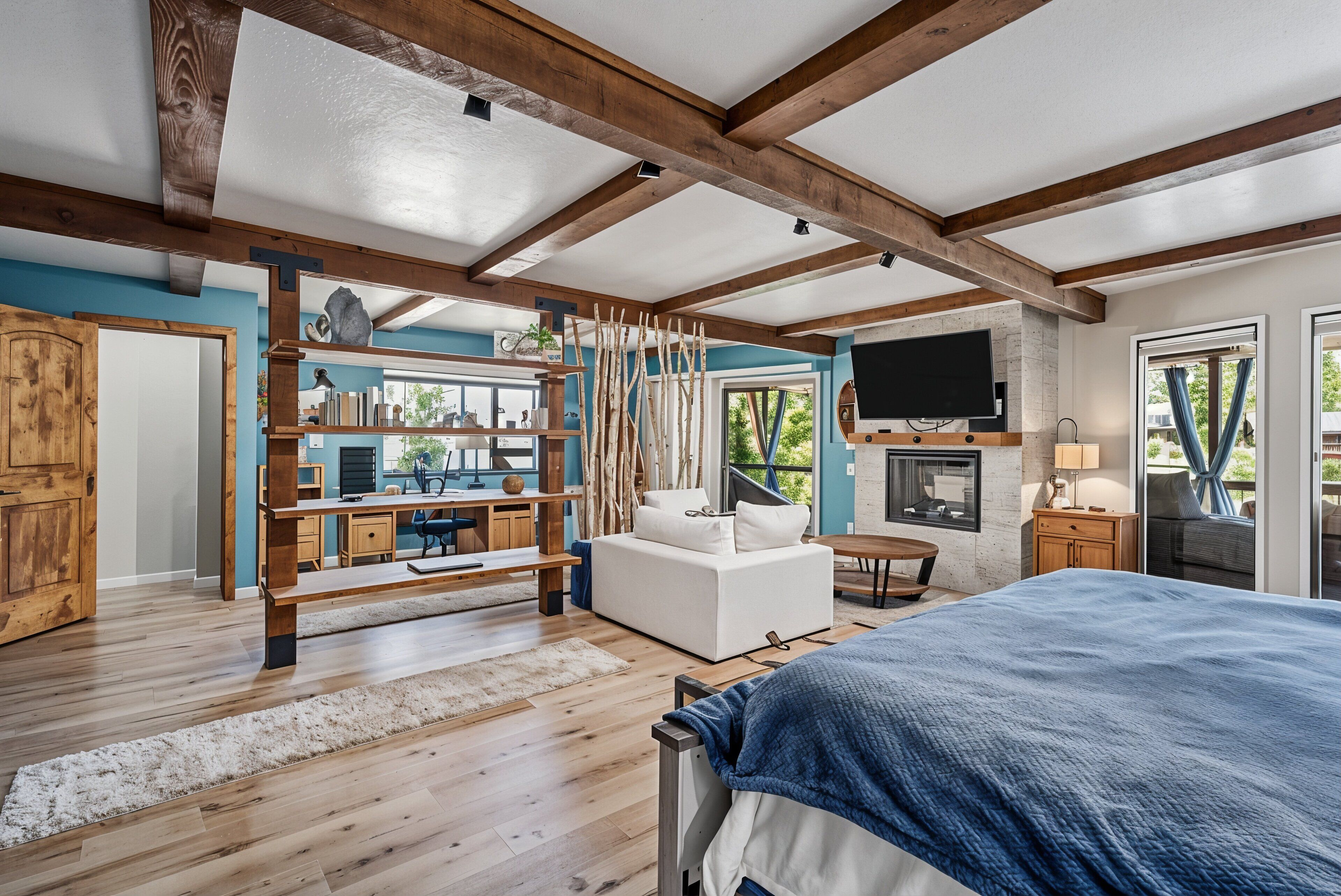Een ruime slaapkamer met een groot bed, houten balken, een televisie en een open haard.