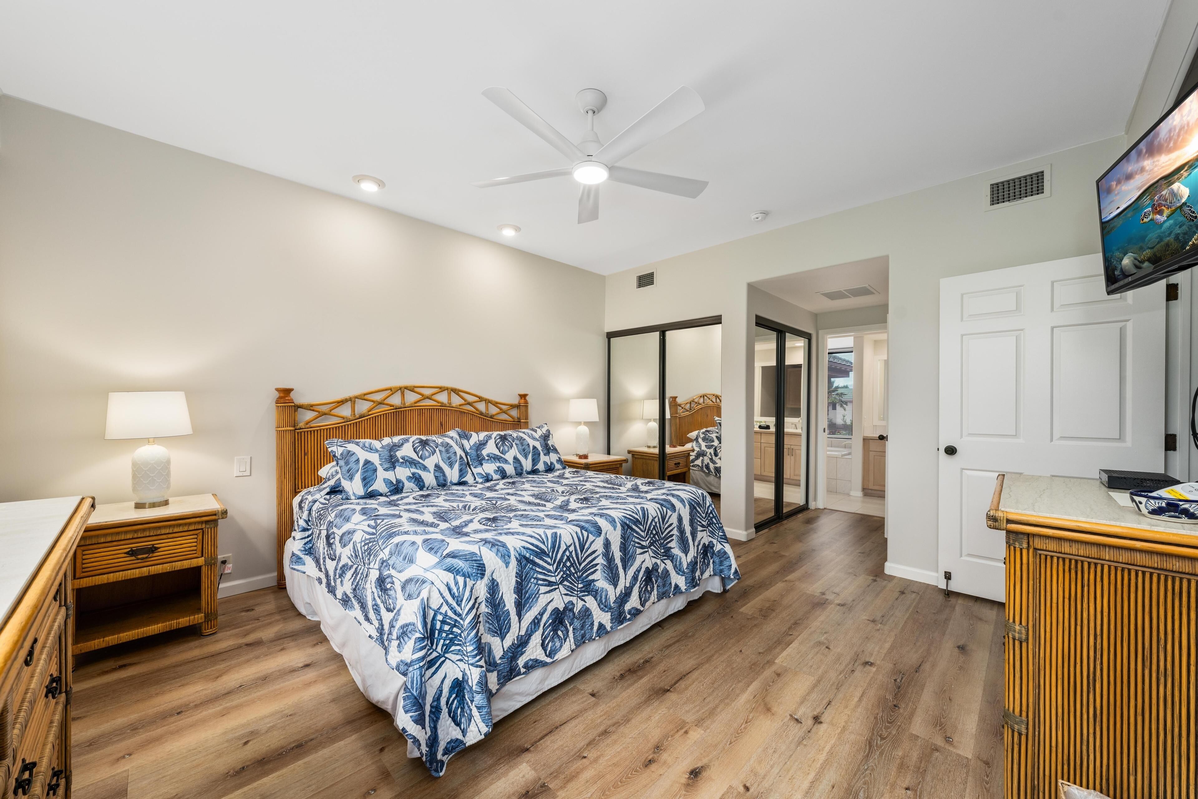 A bedroom with a bed, a nightstand, a television, and a door leading to another room.
