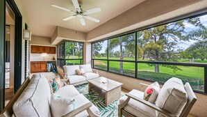 A spacious living area with a large window, a ceiling fan, and a view of a golf course. - Big Island Waikoloa Fairways B-214 2 Bedroom Condo (Waikoloa)
