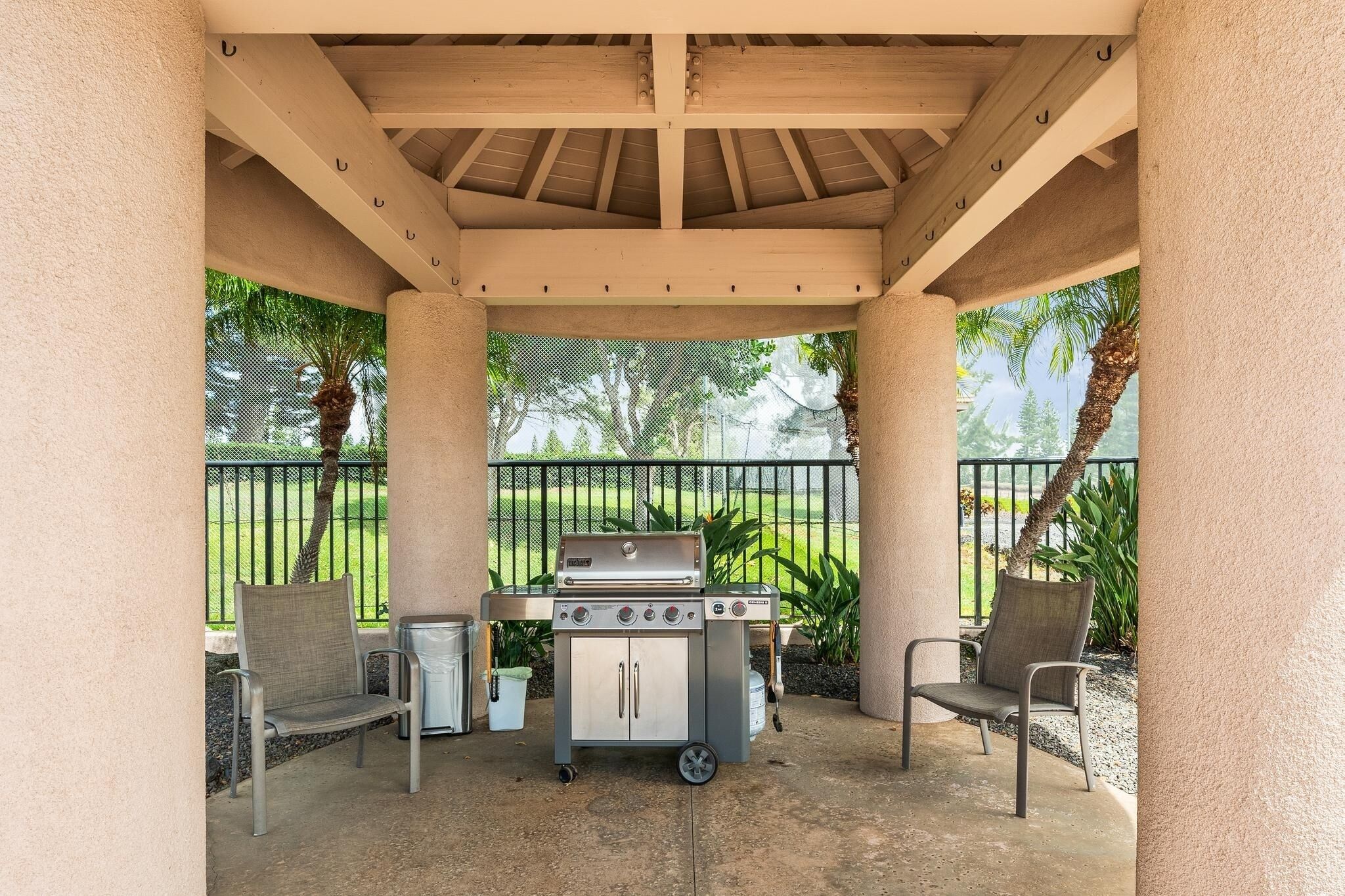 Une terrasse extérieure couverte, équipée d’un barbecue, de deux chaises et d’une petite table.
