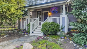 A house with a porch, a stone pathway, and a garden with various plants and flowers. - The French St Retreat 4 Bedroom Home by RedAwning (Breckenridge)