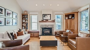 A spacious living room with a fireplace, wooden furniture, and framed pictures on the walls. - The French St Retreat 4 Bedroom Home by RedAwning (Breckenridge)