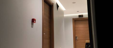 A hallway with wooden doors, a red fire alarm, and a sign indicating room number 104.