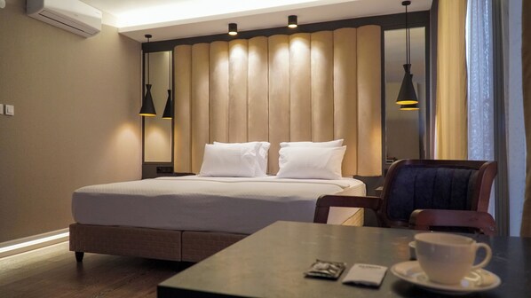 Una habitación de hotel con una cama, una mesa con una taza y un teléfono, y una silla.
